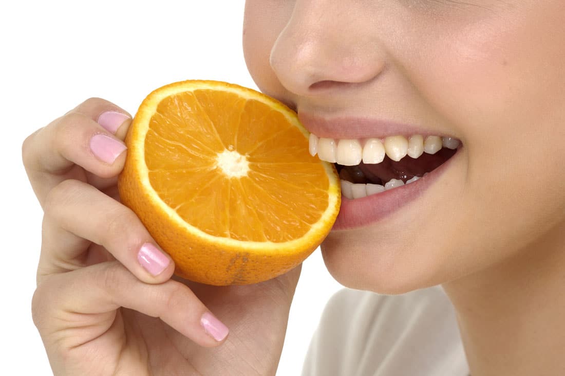 Woman taking a bite of a orange | Avalon Dental, your Carson and El Segundo Dentist