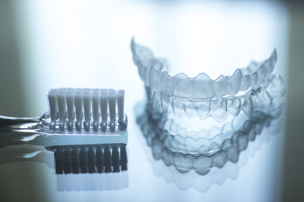 Image of Invisalign clear aligners and a Tooth Brush on a Table | Avalon Dental, your Carson and El Segundo Dentist