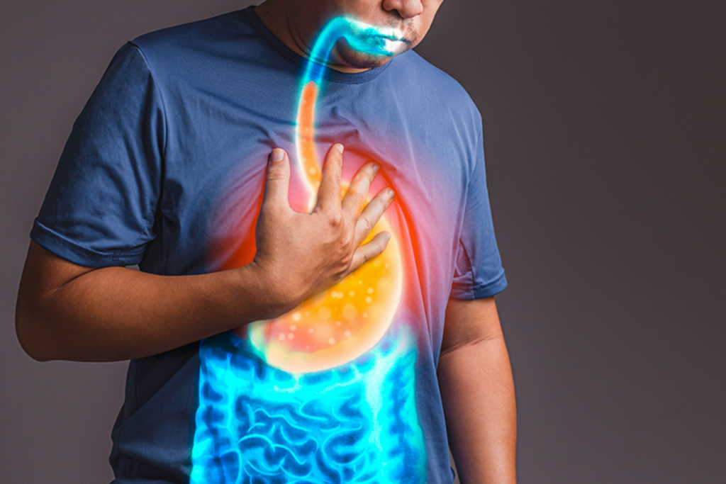 Man clutching his chest with a visual of acid reflux impacting his teeth, for the article 'How Can Acid Reflux Affect My Teeth?