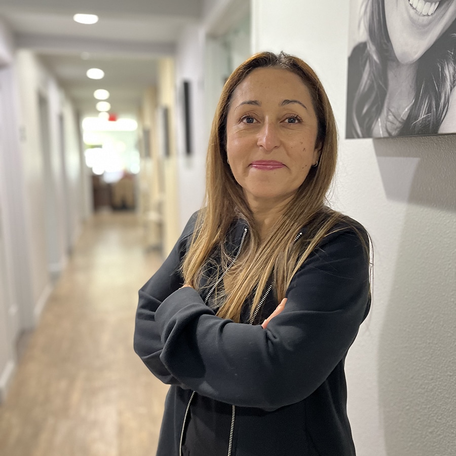 Lucy, the office manager at Avalon Dental Care, smiling confidently in the clinic hallway.